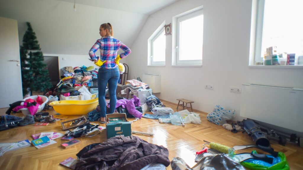 Woman standing in her attic thinking about how she will get rid of all her accumulated junk.