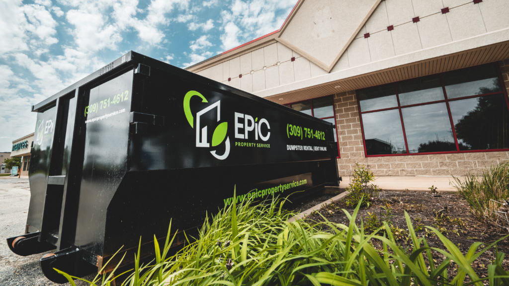 Black roll-off dumpster from EPIC Property Service parked outside a commercial building, with the company logo and phone number displayed on the side